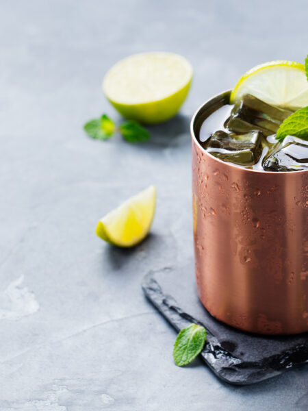 Cold Moscow Mules cocktail with ginger beer, vodka, lime Grey stone background. Copy space